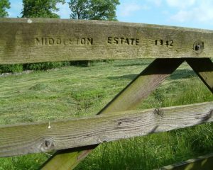 A wooden gate accessing a field. The gate has the words 'Middleton Estate 1942' calved into it.