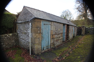 A picture of an old some what dilapidated shed  building like with two light blue doors.